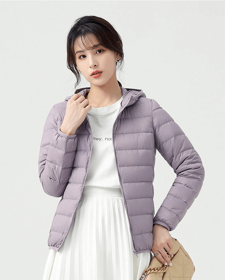 Woman wearing a stylish purple down jacket with hood, perfect for outdoor activities, featuring lightweight nylon and 90% down content for warmth.